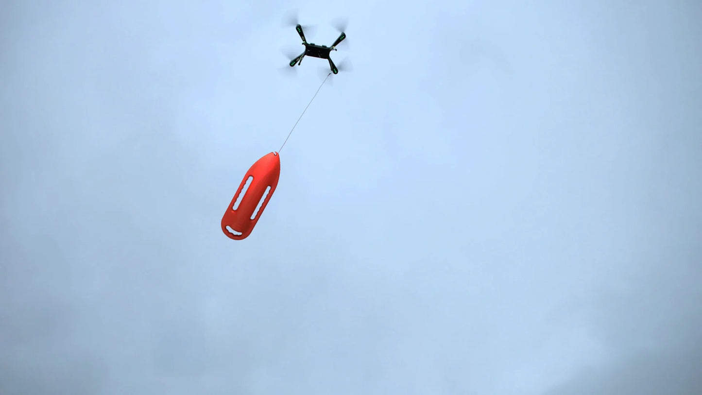Xpece Rescue Drone in flight carrying a red flotation device on a tether during an aerial rescue drop