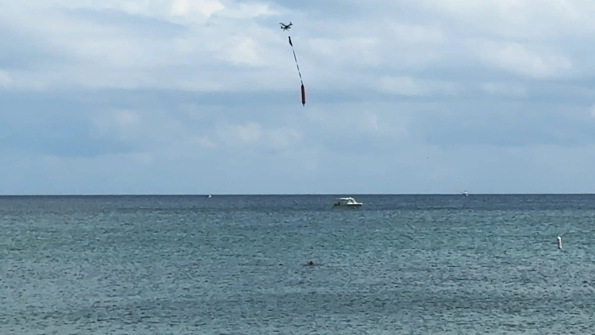 Xpece Rescue Drone flying over the ocean while lowering a flotation device on a tether for rescue support