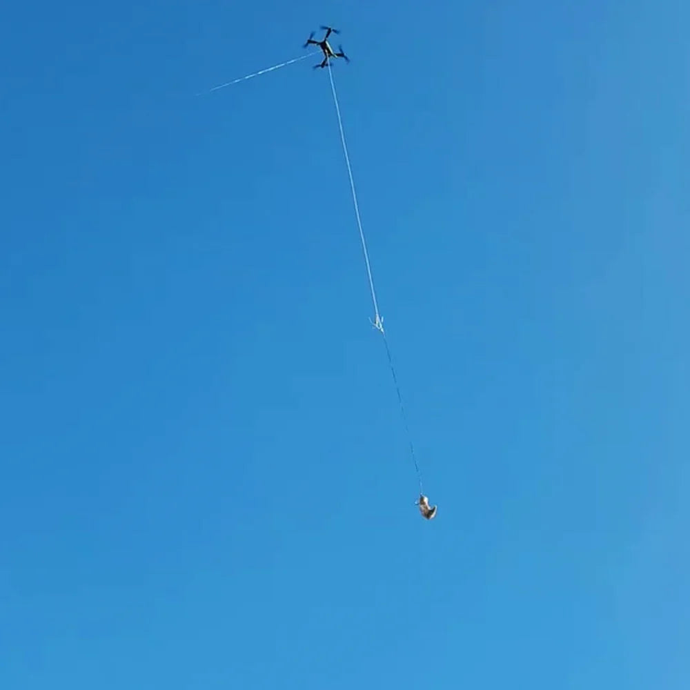 Xpece Rescue Drone flying with a suspended payload on a tether against blue sky